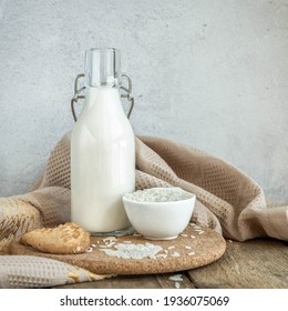 Vegan rice  milk and bowl with a rice  .Non dairy , alternative milk. Healthy vegetarian food and drink concept. Copy space . A bottle of rice milk and raw rice on a wooden table  and a napkin .