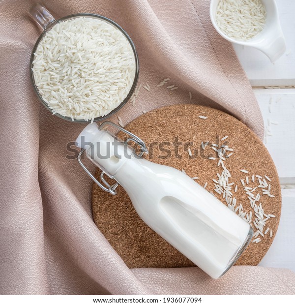 Vegan rice  milk .Non dairy\
, alternative milk. Healthy vegetarian food and drink concept. Copy\
space . A bottle of rice milk and raw rice  . Top view . Flat lay\
milk .