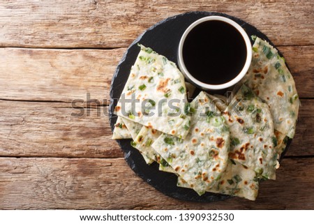 Vegan Scallion Pancakes are a crispy pan-fried Chinese flatbread close-up on a board on the table. horizontal top view from above
