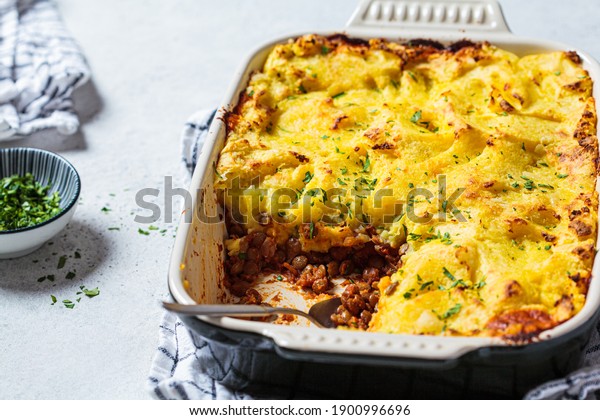 Vegan shepherd\'s pie with\
lentils and mashed potatoes in black backing dish. Vegan food\
concept.