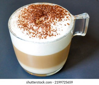 Vegan soy milk cappuccino served in a transparent acrylic cup, against black background