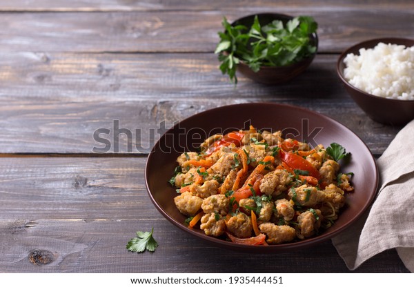 Vegan stew soy meat and vegetables\
served with boiled rice and herbs on a wooden table. delicious\
healthy diet food. selective focus, horizontal,\
space