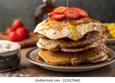 Vegan Strawberry Pancakes With Maple Syrup Drizzle In A Breakfast Setting With Fresh Strawberries, Vegan Sausage, Vegan Eggs, And A Maple Syrup Bottle.