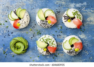Vegan sushi donuts set with pickled ginger, avocado, cucumber, chives, nori and sesame on blue background. Sushi-food hybrids trend. Overhead, top view, flat lay.
