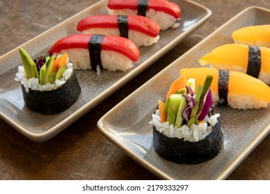 Vegan sushi: nigiri with red pepper and golden tomato topping and futomaki with carrot, avocado, cucumber and red cabbage.