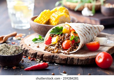 rap de tortilla de légumes, rouleau avec des légumes grillés et de la lentille et du maïs bouilli sur fond bois