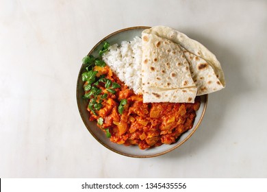 Vegan vegetarian curry with ripe yellow jackfruit served in ceramic bowl with rice, coriander and homemade flatbread flapjack over white marble background. Flat lay, space