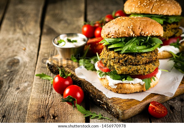 Vegan zucchini burger and ingredients on rustic\
wood background, copy\
space