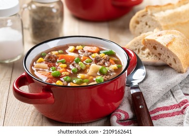 Vegetable Beef Soup In A Red Bowl On A Rustic Wooden Table