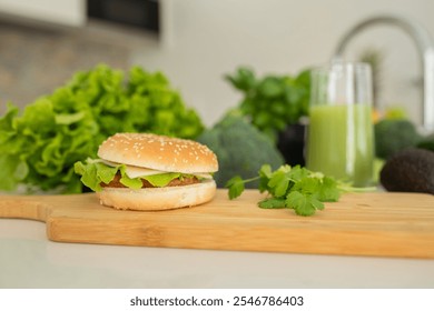 A vegetable burger topped with lettuce sits on a wooden cutting board, surrounded by fresh greens and a glass of green smoothie, showcasing healthy eating in a contemporary kitchen setting. - Powered by Shutterstock