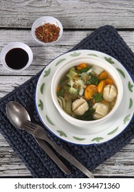 Vegetable Clear Soup With Chicken Meat Balls Served In White Bowl On  Crochet Place Mat Along With Soy Sauce And Fried Shallot On White Rustic Wooden Table. Healthy Food. Selective Focus. 