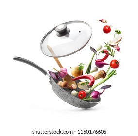 Vegetable composition. Frying pan with lid and flying vegetables, isolated on white background