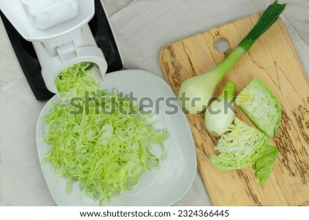 Сabbage in a vegetable cutter on kitchen table. Chopped cabbage is falling into a bowl. Homemade healthy food.