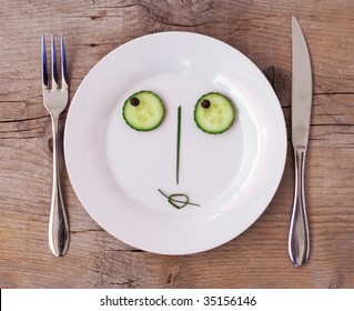 Vegetable Face on Plate with knife and fork, set on wooden board - Female, Flirting - Powered by Shutterstock