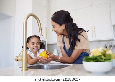 Vegetable, family and washing with a girl and mother cleaning a pepper in the kitchen of the home together for hygiene. Kids, health and cooking with a woman and daughter using a basin to rinse food - Powered by Shutterstock