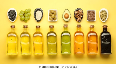 Vegetable fats. Different oils in glass bottles and ingredients on yellow table, flat lay