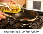 Vegetable fats. Woman pouring oil into frying pan on stove, closeup