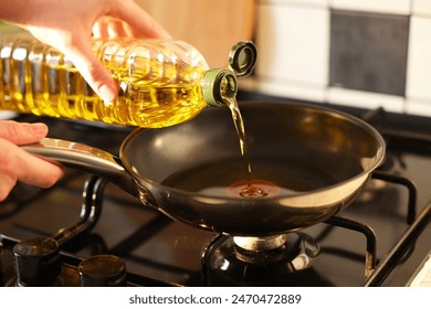 Vegetable fats. Woman pouring oil into frying pan on stove, closeup - Powered by Shutterstock