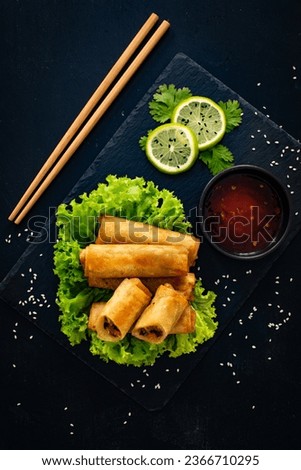Vegetable filled spring rolls and sauces on wooden table 