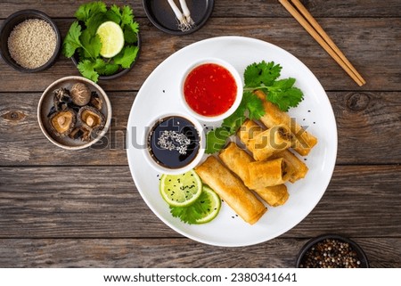 Vegetable filled spring rolls and sauces on wooden table 