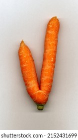 In a vegetable garden. Organic Agriculture. Double carrot, which took the form of the letter V. Like the V for victory. On light background.