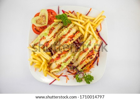 Vegetable Jumbo Grilled Sandwich served with french fries, club sandwich with tomato, cucumber, beetroot and onion, selective focus isolated in white background