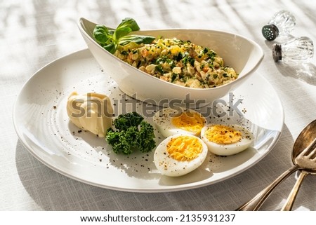 Vegetable mayonnaise salad with hard boiled eggs on white table 