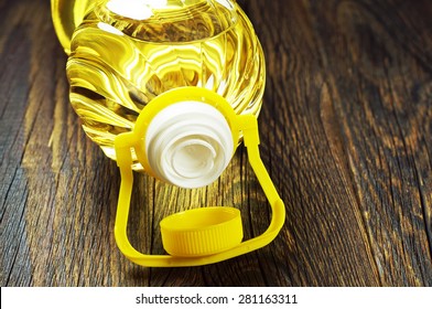 Vegetable oil in plastic bottle on old wooden table closeup