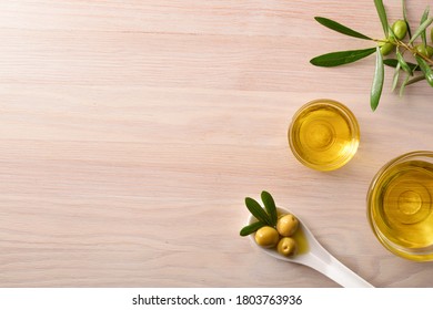 Vegetable Olive Oil In Glass Bowls On Kitchen Bench With Spoon And Olive Branch. Top View.