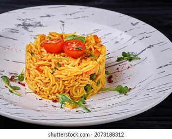 Vegetable rice served in culinary ring on white plate on wooden background. 
boiled basmati, rice with tomato, bell pepper, green peas served with greens. Restaurant menu side dish. Veggie garnish