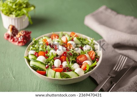 Vegetable salad with cheese and pomegranate grains on a green background