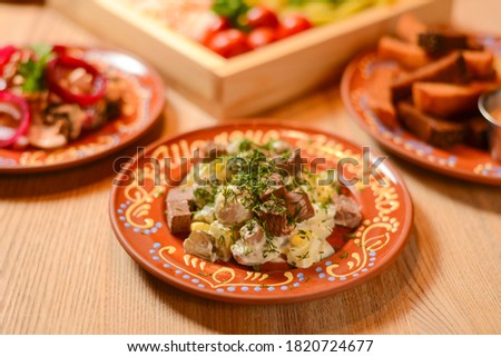 Vegetable salad with mayonnaise. Delicious mayonnaise salad on a plate. Over rustic wooden background. Ukrainian cuisine concept.