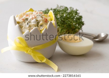 Vegetable salad with mayonnaise in eggshell shaped bowl, egg and cress, easter food concept