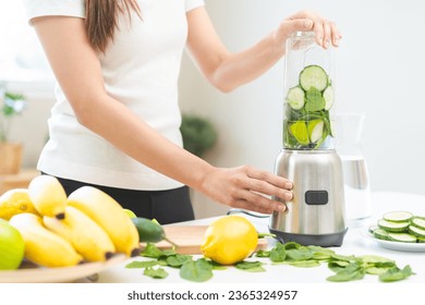 Vegetable smoothie detox, woman hand making healthy raw fresh green fruit juice with blender machine, preparing drink with spinach in kitchen at home, eating vegan diet. Healthy dieting, weight loss. - Powered by Shutterstock