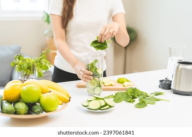 Vegetable smoothie detox, woman hand making healthy raw fresh green fruit juice with blender machine, preparing drink with spinach in kitchen at home, eating vegan diet. Healthy dieting, weight loss. - Powered by Shutterstock