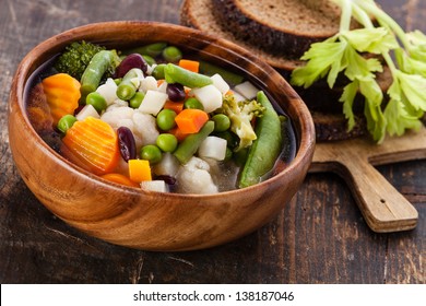 Vegetable soup with bean, pea, carrot and potato in wooden bowl