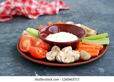 Vegetable Tray With A Ranch Dip On A Dark Background. Raw Vegetable Mix Includes Sliced Mushrooms, Carrots, Celery, Tomatoes.