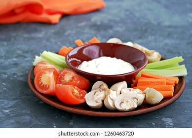 Vegetable Tray With A Ranch Dip On A Dark Background. Raw Vegetable Mix Includes Sliced Mushrooms, Carrots, Celery, Tomatoes.