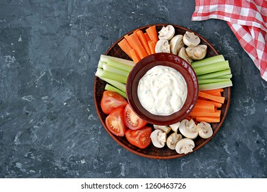 Vegetable Tray With A Ranch Dip On A Dark Background. Raw Vegetable Mix Includes Sliced Mushrooms, Carrots, Celery, Tomatoes.