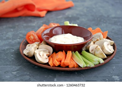 Vegetable Tray With A Ranch Dip On A Dark Background. Raw Vegetable Mix Includes Sliced Mushrooms, Carrots, Celery, Tomatoes.