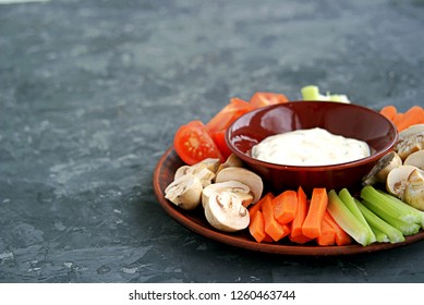 Vegetable Tray With A Ranch Dip On A Dark Background. Raw Vegetable Mix Includes Sliced Mushrooms, Carrots, Celery, Tomatoes.