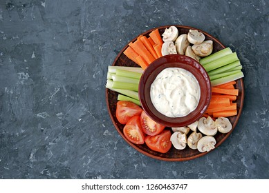 Vegetable Tray With A Ranch Dip On A Dark Background. Raw Vegetable Mix Includes Sliced Mushrooms, Carrots, Celery, Tomatoes.