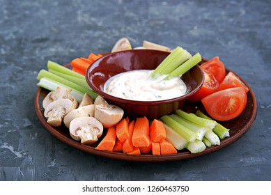 Vegetable Tray With A Ranch Dip On A Dark Background. Raw Vegetable Mix Includes Sliced Mushrooms, Carrots, Celery, Tomatoes.