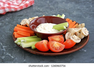 Vegetable Tray With A Ranch Dip On A Dark Background. Raw Vegetable Mix Includes Sliced Mushrooms, Carrots, Celery, Tomatoes.