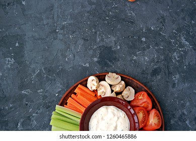 Vegetable Tray With A Ranch Dip On A Dark Background. Raw Vegetable Mix Includes Sliced Mushrooms, Carrots, Celery, Tomatoes.