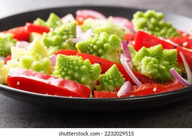 Vegetable vegan salad of Romanesco broccoli, bell pepper and red onion sprinkled with sesame seeds close-up in a plate on the table. Horizontal
