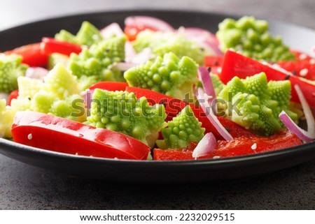 Vegetable vegan salad of Romanesco broccoli, bell pepper and red onion sprinkled with sesame seeds close-up in a plate on the table. Horizontal