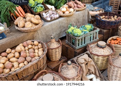 Vegetables and drinks for sell in vintage street market. Potatos, carrots,green cauliflower,garlic, onions and cabbage in wood and osier baskets.