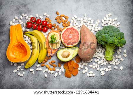 Vegetables, fruit and foods containing potassium over gray stone background, top view. Natural sources of potassium, vitamins and micronutrients for healthy balanced diet and avitaminosis prevention Stock foto © 