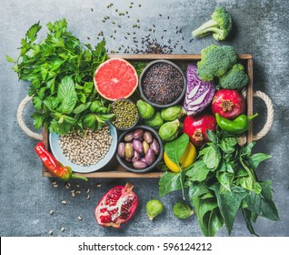 Vegetables, fruit, seeds, cereals, beans, spices, superfoods, herbs, condiment in wooden box for vegan, gluten free, allergy-friendly, clean eating or raw diet. Grey concrete background and top view